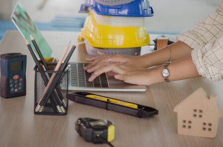 hand professional architect, engineer or interior hands working with laptop and safety helmet on...