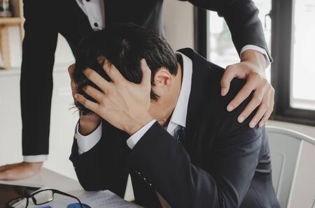 sadness asian business man upset about life problems with support from his best friend and sitting in home office, encouragement, fired from job, business problem, financial and investment conceptの写真素材