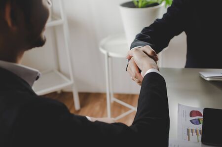Deal. business people smiling and shaking hands with partner after finishing up a meeting with document on desk in office room, partnership, negotiation, business meeting and teamwork conceptの写真素材