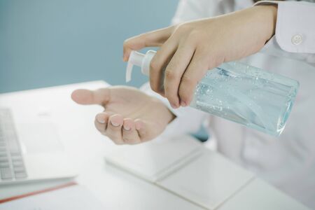 business man washing hand with alcohol gel for clean corona virus (covid19) prevention and work from home, health care, virus outbreak protection, cleaning hand, self quarantine and stay home conceptの写真素材