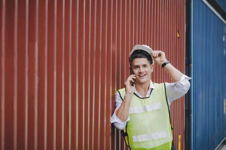 handsome caucasian engineer control worker talking on digital mobile phone standing with cargo...