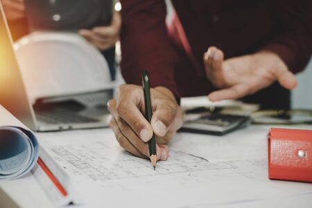 hands of group engineer and architect working on blueprint and laptop computer on workplace desk in meeting room project at construction site office, contractor, engineering and construction conceptの写真素材