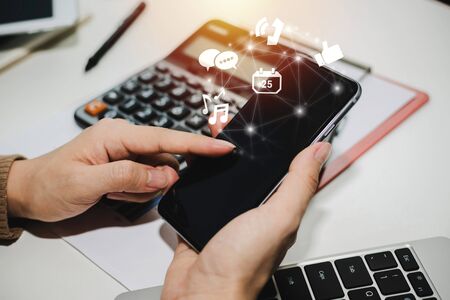 5G. hand using social network on digital mobile phone with virtual digital icon, calculator and report on desk at home office, digital marketing, work from home, business finance, technology conceptの写真素材