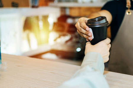 young happy handsome man barista serving hot coffee cup to friendly female customer over counter in modern cafe coffee shop, cafe restaurant, service mind, small business owner food and drink conceptの写真素材