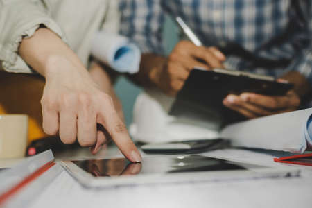 group of hand interior designer and architect working on mobile tablet and blueprint in meeting room at construction site office, interior design, contractor, engineering and construction conceptの写真素材