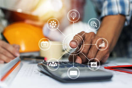 hands of interior designer and architect pointing on blueprint and safety helmet with virtual digital icon in meeting room at construction site office, contractor, engineering and construction conceptの写真素材