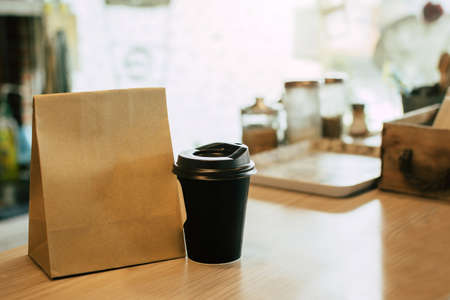 hot black coffee cup and dessert paper set bag waiting for customer on counter in modern cafe coffee shop, food delivery, cafe restaurant, takeaway food, small business owner, food and drink conceptの写真素材