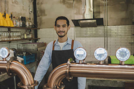 handsome asian waitress service man or bartender with apron near counter smiling and looking at...