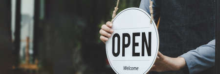 wide banner. Reopen. waitress hand turning open sign board on glass door in modern cafe coffee shop ready to service, cafe restaurant, retail store, small business owner, food and drink conceptの写真素材