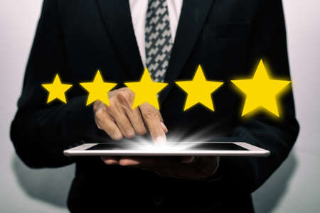 5 star rating. business man customer hand touching on mobile tablet with five star button to review...