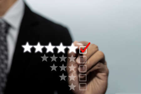 Quality control. businessman hand checking mark five star rating on checklist box with pen to review good rating, digital marketing, checklist planning, good experience, customer feedback conceptの写真素材