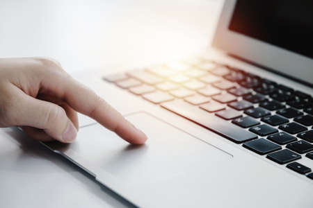 people hand touching touchpad on laptop computer on desk at home office, work from home, searching web, social network, online, business strategy, finance, investment and digital technology conceptの写真素材
