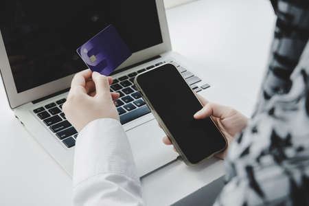 Shopping Online. hand holding credit card and online shopping on laptop computer on desk at home...