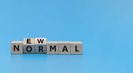 COVID-19. word NEW NORMAL flipping written on wooden cube block stack on blue background, virus prevention, coronavirus pandemic, self quarantine, social distancing and new normal lifestyle conceptの写真素材