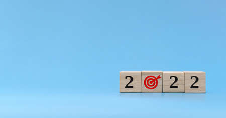 New year goal. number and dart board icon written on wooden cube block stack on blue background, change from 2021 to 2022, new year congratulation, countdown to 2022, goal and target plan conceptの写真素材