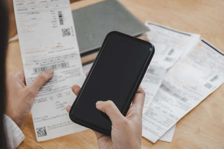 woman hand entering password code on mobile phone paying bill with credit card bill on desk in home office, internet, digital marketing, mobile banking, online payment and digital technology conceptの写真素材