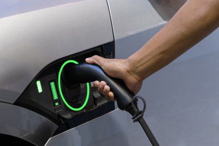 EV Car. driver hand fill up with power cable supply plugged station for electric vehicle charging at...