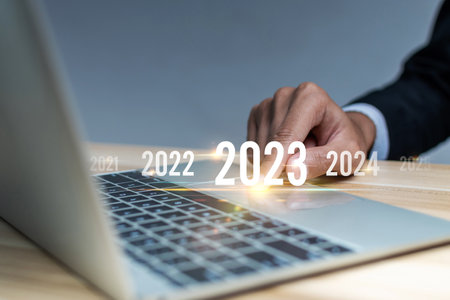 2023. businessman hand touching and pointing on year 2023 with digital laptop computer, goal target, change from 2022 to 2023, strategy, finance, investment, business planning, happy new year conceptの写真素材