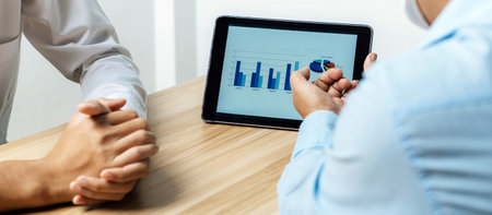 cropped view group of business people discussing financial graph chart on mobile tablet together in meeting room, online marketing, business finance meeting, investment, digital technology conceptの写真素材