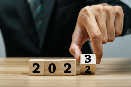 businessman hand putting wooden cube with number change from 2022 to 2023, business year, new year congratulation, quarterly report, business plan, countdown to 2023, goal and target planning conceptの写真素材