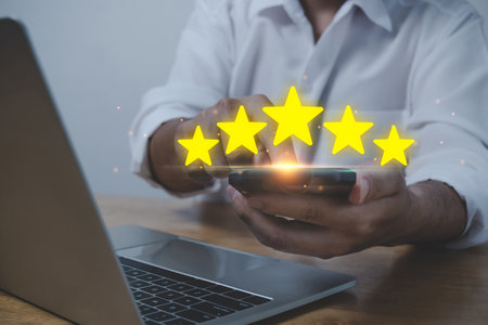 business man using mobile smart phone and laptop computer with five star button to review good rating, digital marketing, good experience, customer product rating review, customer feedback conceptの写真素材