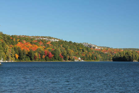 Autumn landscape  Rocky ridges, colourful trees and clear blue lakeの写真素材
