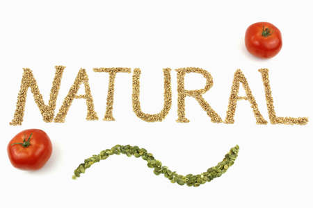 Natural written with wheat kernels, tomatoes and pumpkin seeds on white backgroundの写真素材
