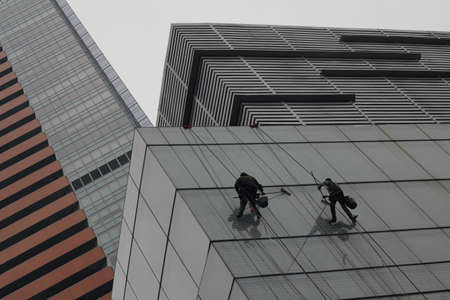 Men cleaning skyscraper windows, climbing with ropes in Chinaのeditorial素材