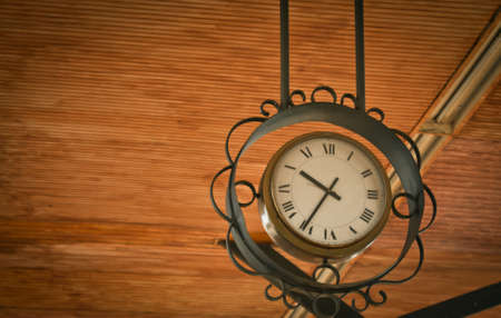 Low angle view of hanging vintage clock against wood ceilingの写真素材