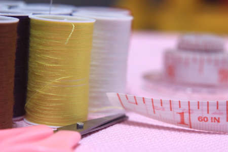 Flat lay or top view, Needle Scissor, Thread, Tailor Meter, Scissor at Pink Background