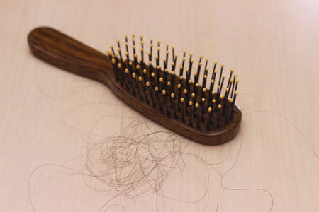 close up top view hair fall at white brown plastick comb at wooden table