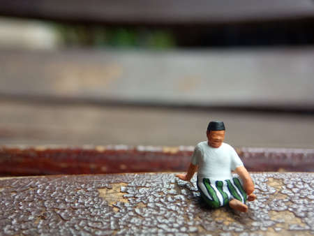 Mini figure toy old man sit at scratch wooden chair, with copy or negative space for text placement areaの写真素材