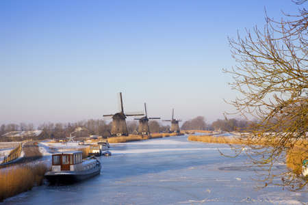 Windmill in winter time with snow and blue skyの写真素材