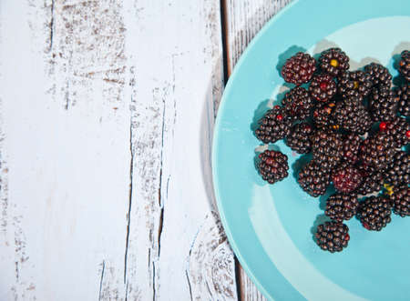 Blackberries on blue plate on wooden backgroundの写真素材