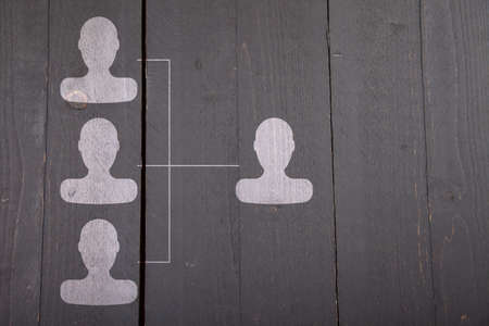 White organigram with white heads on dark black wooden background