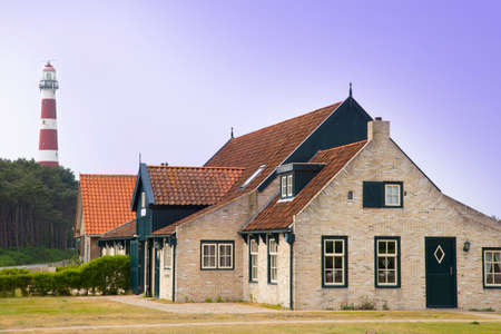 Ameland, The Netherlands - May 21, 2016: Typical old farmer house on the island Ameland, The Netherlands with famous lighthouse.のeditorial素材