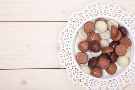 Traditional Dutch chocolate candy pepernoot on white plate on white wooden backgroundの写真素材