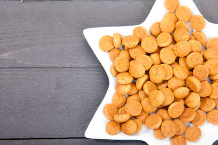 Traditional Dutch candy pepernoot on white plate on white wooden backgroundの写真素材