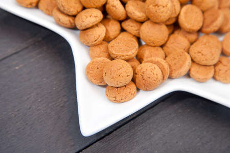 Traditional Dutch candy pepernoot on white plate on white wooden backgroundの写真素材