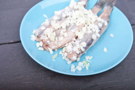 Traditional Dutch raw herring with onions on plate on wooden backgroundの写真素材