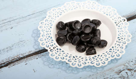 Traditional Dutch candy drop on little plate on wooden backgroundの写真素材