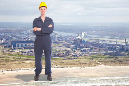 Giant young worker with steel factory on backgroundの写真素材