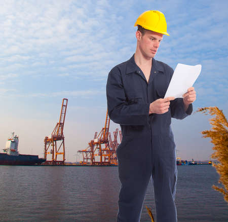 Young worker at harbor with cranes on backgroundの写真素材