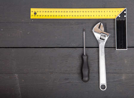 Square, hammer and screwdriver on wooden background