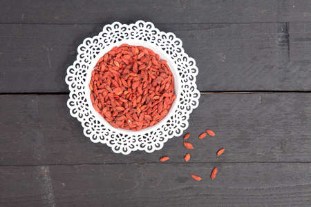 Dried goji berries in white bowl on wooden backgroundの写真素材