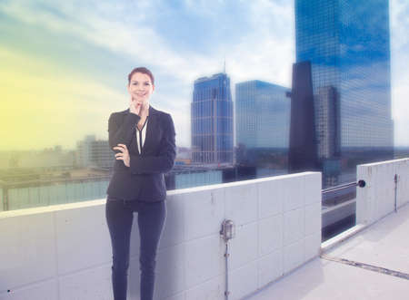 Young business woman standing with office skylineの写真素材