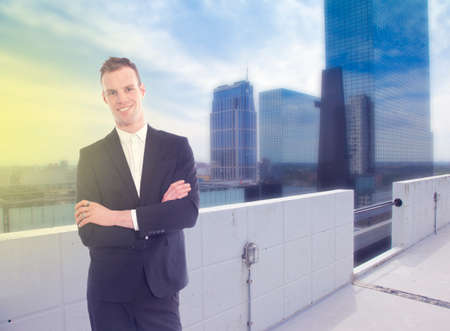 Young business man standing with office building backgroundの写真素材