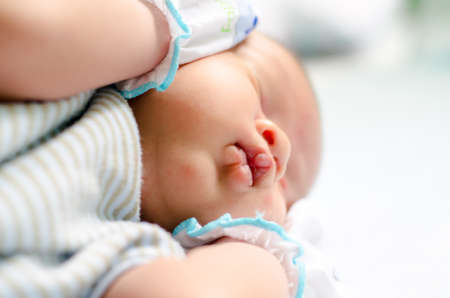 Peaceful baby lyingand crying on a bed while sleeping in a bed room: close up on mouthの写真素材