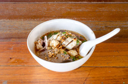Spicy Noodle in a white bowl on wooden background. The favorite meal for lunch. Thailand food.