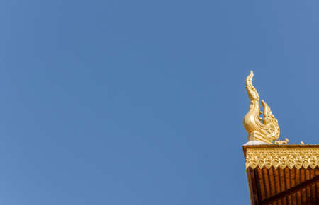 Golden symbol on roof top at thai temple on blue sky backgroundの写真素材